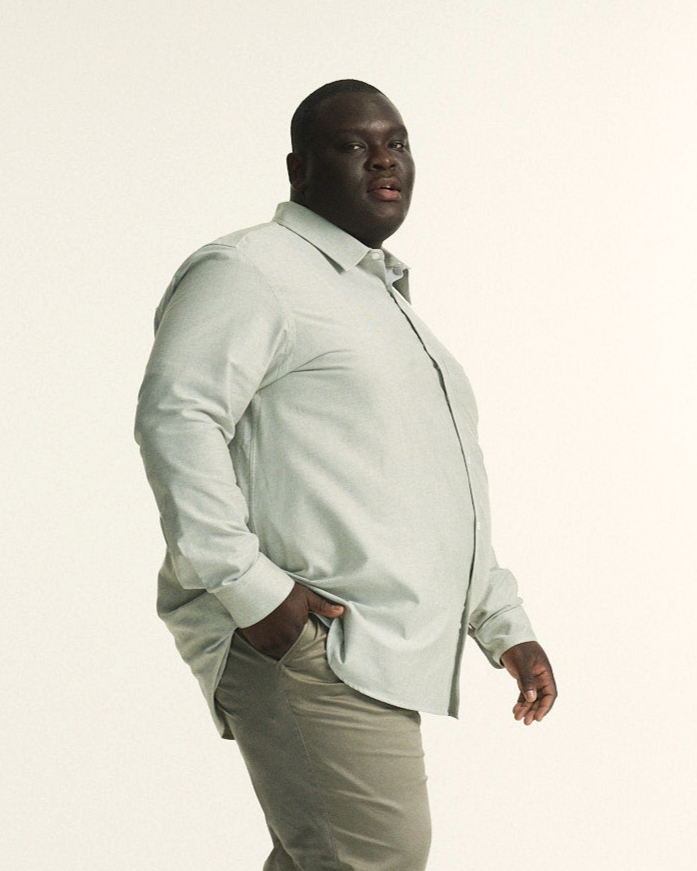 Model wearing The Tailored Oxford Shirt in Khaki, showcasing a classic fit designed for plus-size men and The Stretch Chino in Khaki, in regular fit, tailored for plus-size men with a comfortable elastic waistband