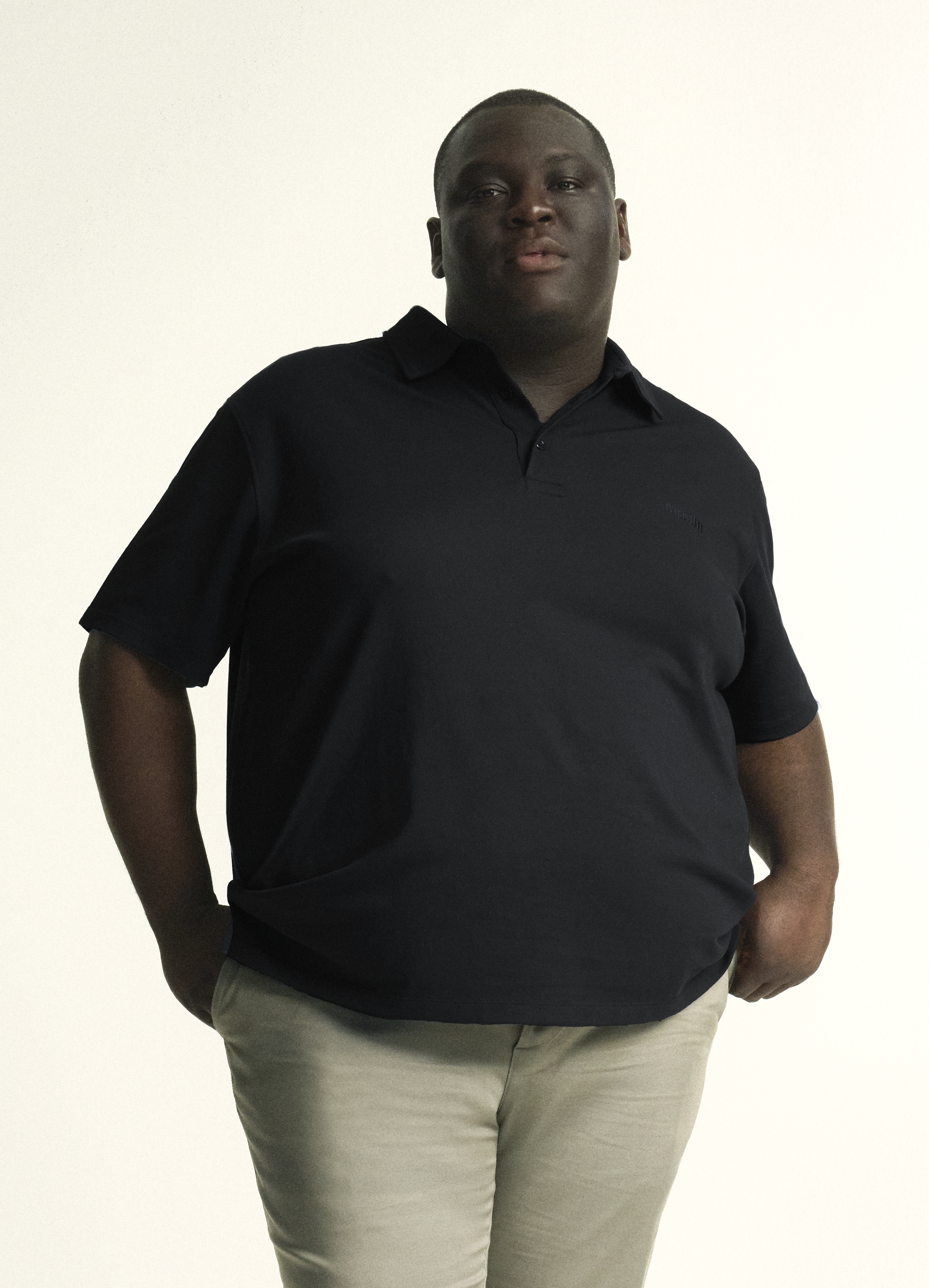 Model wearing plus size short sleeve mens breathable piqué polo in sizes XL-5XL, in black