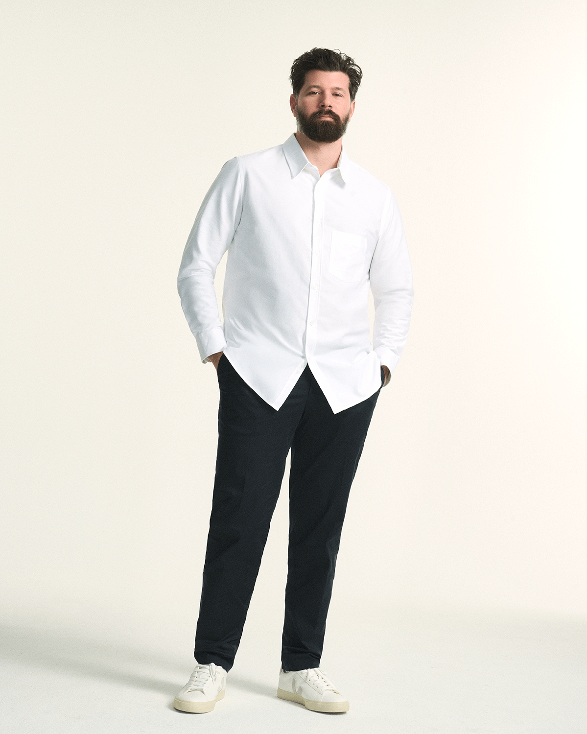 Model wearing The Tailored Oxford Shirt in White, showcasing a classic fit designed for plus-size men and The Stretch Chino in Navy, in regular fit, tailored for plus-size men with a comfortable elastic waistband 